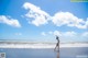 A woman standing on a beach with her arms in the air.