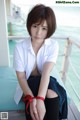 A woman in a white shirt and black skirt sitting on a bench.