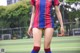 A woman in a soccer uniform is standing on a field.