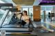 A woman is sitting on a treadmill in a gym.