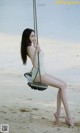 A woman sitting on a swing on the beach.