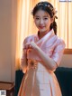 A woman in a pink and gold hanbok poses for a picture.