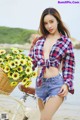 A woman standing next to a bike with a basket of sunflowers.