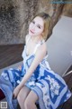 A woman in a blue and white dress sitting on a chair.