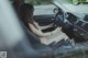 A naked woman sitting in the driver's seat of a car.