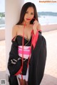 A woman in a black and pink kimono posing for a picture.