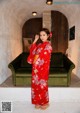 A woman in a red kimono standing in front of a green couch.