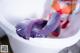 A woman in a bathtub with purple gloves on.