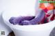 A woman in a bathtub with purple rubber gloves.