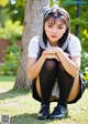 A young woman sitting on the ground in a park.