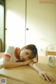 A woman laying on top of a wooden table next to a clock.