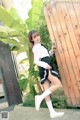 A woman in a school uniform leaning against a wooden fence.