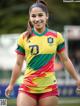 A woman in a colorful shirt and shorts on a soccer field.