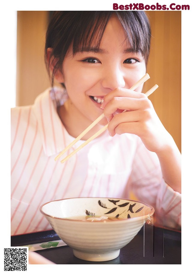 A young girl holding chopsticks over a bowl of soup.