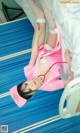 A woman in a pink nurse outfit laying on a hospital bed.