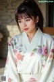 A woman wearing a white kimono with pink flowers on it.