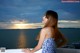 A woman in a blue and white dress standing on a balcony overlooking the ocean.