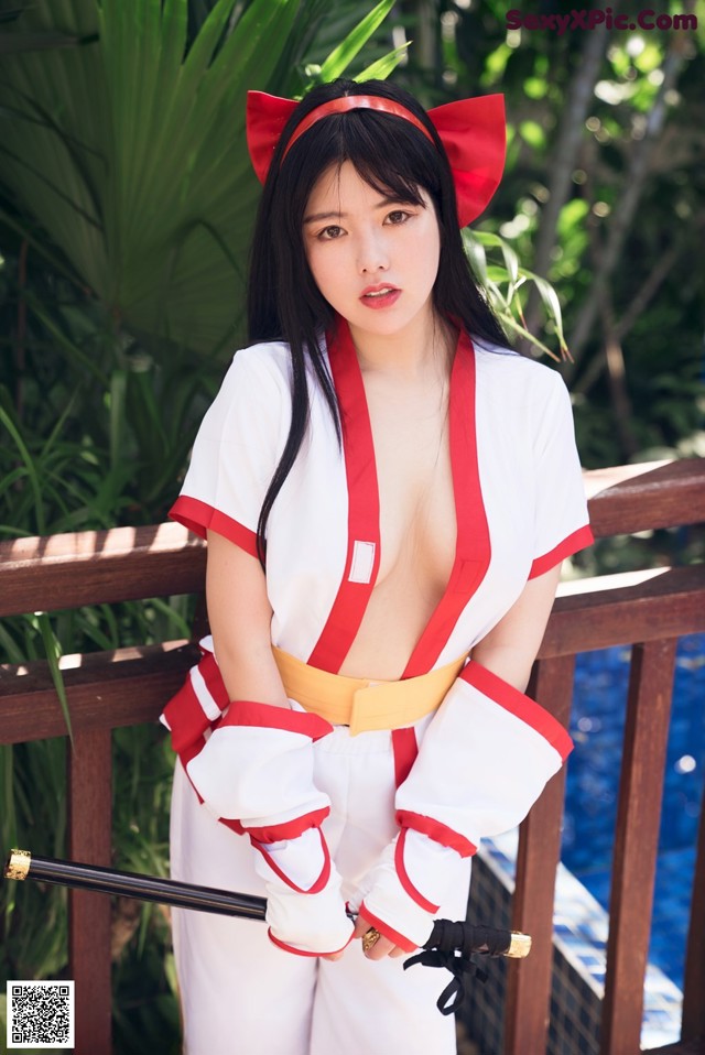 A woman in a red and white outfit holding a sword.