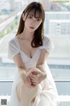 A woman in a white dress sitting on a window sill.