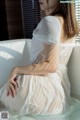 A woman sitting in a bathtub wearing a white dress.