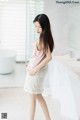 A woman standing in a bathroom next to a bathtub.