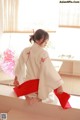 A woman in a white kimono sitting on a window sill.