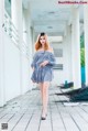 A woman in a blue and white striped dress walking down a walkway.