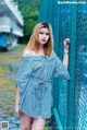 A woman in a blue and white striped dress leaning against a fence.