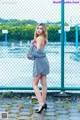 A woman standing in front of a chain link fence.