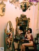 A naked woman sitting in front of a mirror in a room.